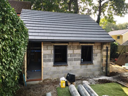 Newly constructed house with a slate roof, stone walls, and uninstalled windows.