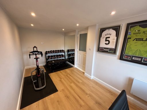 Modern indoor fitness room featuring exercise equipment and framed sports jerseys.